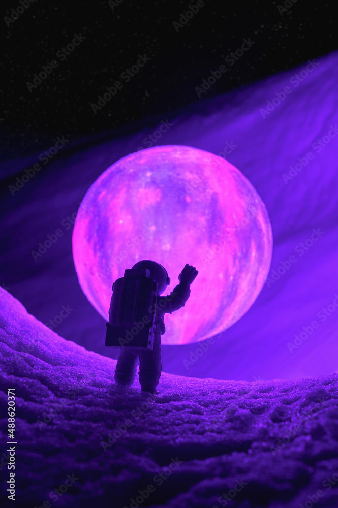 Silhouette of the toy of astronaut against levitating glowing sphere over surface icy planet covered with snow. Concept of space travel, exploration, and colonization. Vertical orientation
