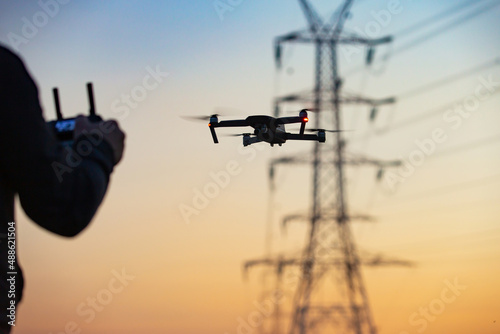 A concept of a man flying a drone collecting a data remotely from a power tower station photo