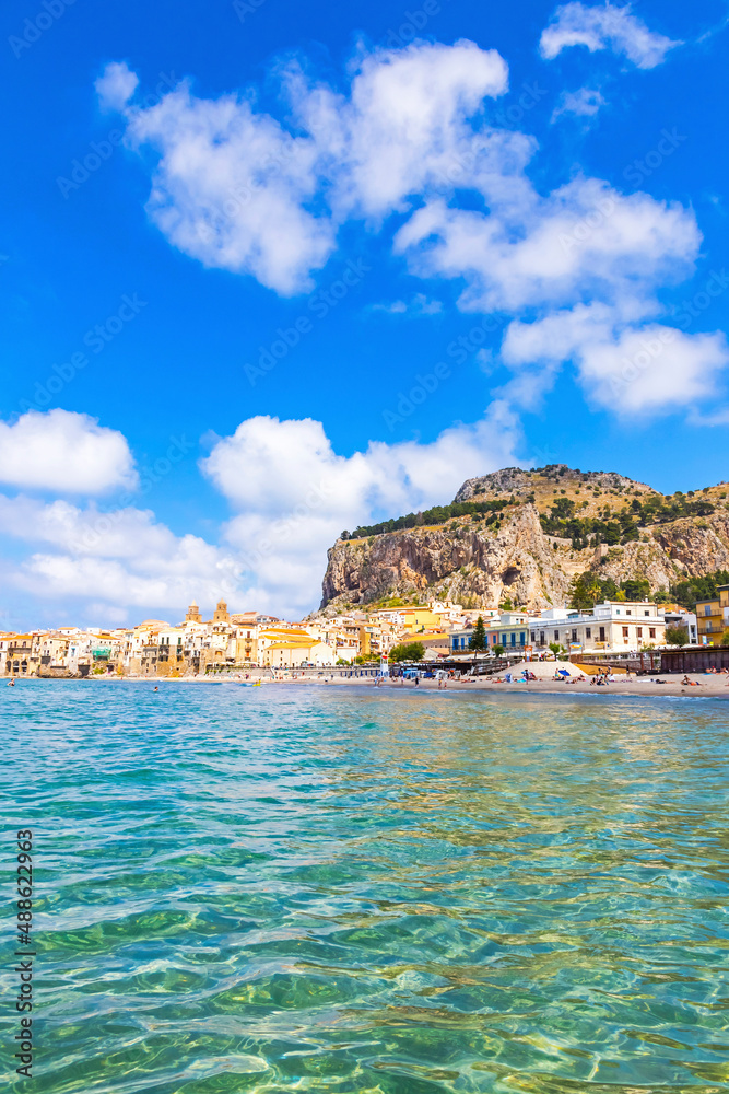 Azure water of Mediterranean sea at Cefalu beach, Cefalu town, Sicily, Italy. One of the best beach on Sicily. Mount La Rocca di Cefalu on background