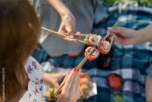 Three hands with chopsticks and sushi. Top view