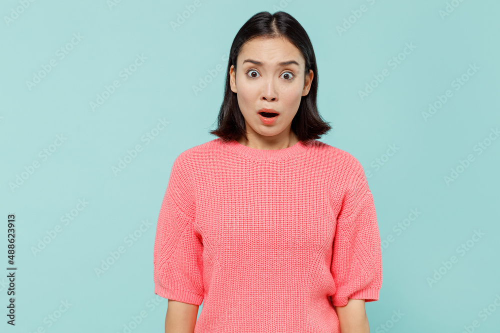Fototapeta premium Young shocked surprised woman of Asian ethnicity 20s wearing pink sweater look camera with opened mouth isolated on pastel plain light blue color background studio portrait. People lifestyle concept.