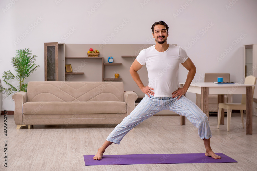 Fototapeta premium Young man doing sport exercises at home