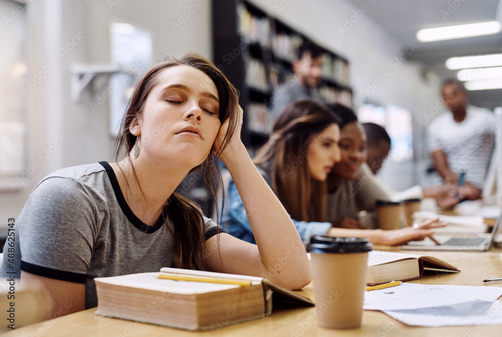 Im just closing my eyes for a bit. Shot of a young woman looking tired while studying in a college library in the library. Im just closing my eyes for a bit. Shot of a young woman looking tired while studying in a college library in the library.