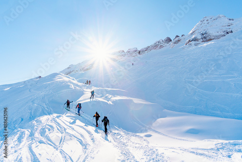 Group of alpinist people going on top of moutain with ski gear during a sun day without cloud photo