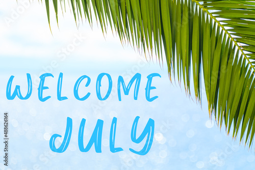 Welcome July text on the background with palm leaf and blue sea. Template of a greeting card, postcard or advertisement of a tour agency. 