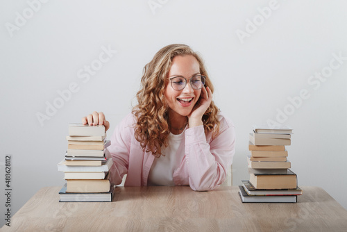 a girl looks at a large stack of books
