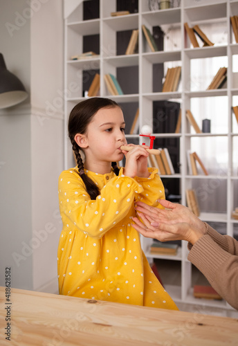 a little girl is sitting at a table and doing speech therapy exercises. Problems with pronunciation