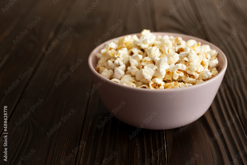 Bowl with popcorn on dark wooden table with copy-space