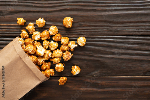 Obraz na płótnie Caramelized popcorn in paper bag on wooden kitchen table flat lay w salonie