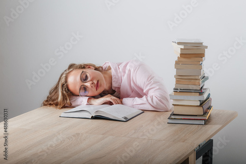 The girl fell asleep at the desk while reading