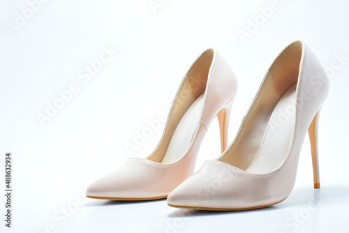 Zapatos blancos de tacón alto para mujer. Calzado formal, para fiesta o trabajo sobre un fondo blanco. Espacio para texto al lado izquierdo.