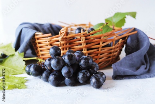 Bunch of grapes  wicker basket with berries and linen drapery on the table  still life  home cooking  harvest season