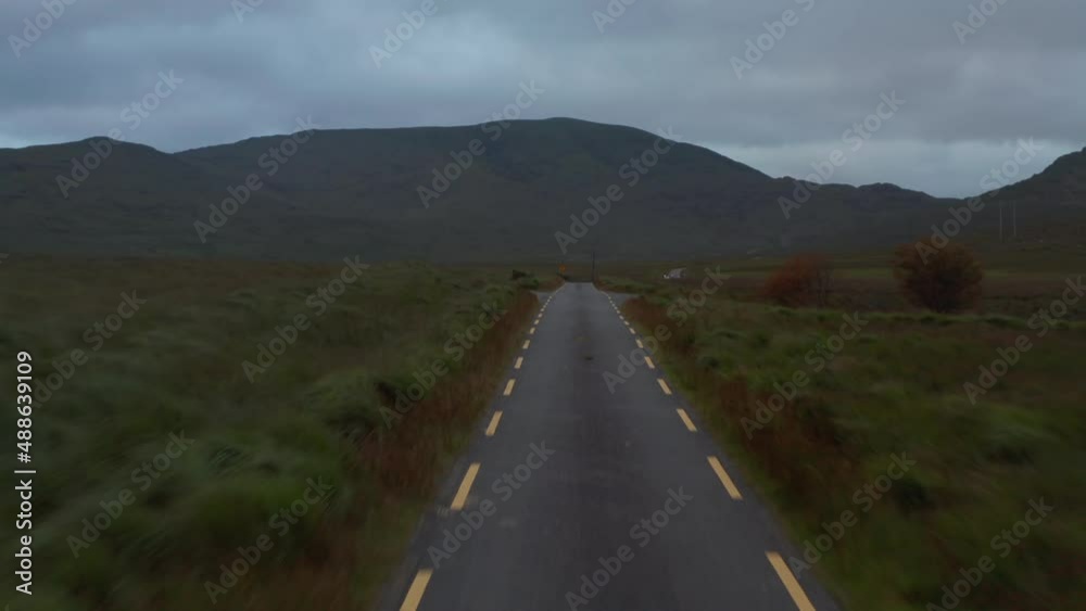 Low flight above narrow road in countryside. Ascending and revealing oncoming offroad car with trailer. Mountain ridge in background. Ireland Low flight above narrow road in countryside. Ascending and revealing oncoming offroad car with trailer. Mountain ridge in background. Ireland