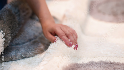 Woman touching a gray carpet close-up. Close-up of a hand touching a soft carpet. Gentle and fluffy carpet between the fingers.