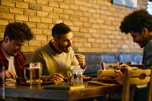 Young male friends enjoy in lunch together in a pub.