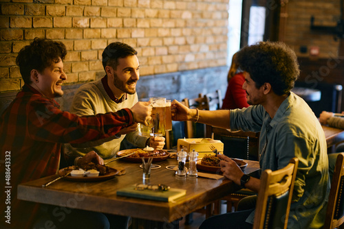 Multiracial group of happy men toast with beer during their lunch in pub.