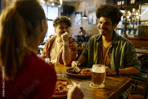 Happy Lebanese man enjoys in conversation with his friends during their lunch in pub.
