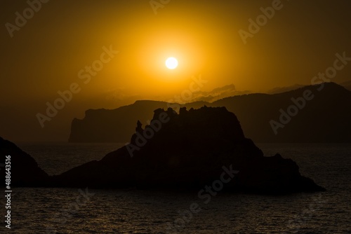 Silhouette of rocks in the sea and the island in the setting sun. Malgrat, Mallorca. Positive energy and warm colors. photo