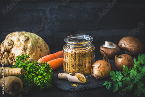 Homemade vegetable broth powder, organic vegetable stock, with raw vegetables on black background, copy space