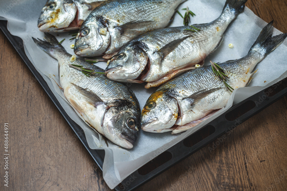 Fresh dorado fish on a baking sheet, ready for baking in the oven Fresh dorado fish on a baking sheet, ready for baking in the oven