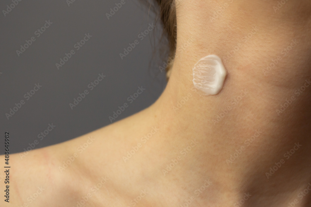Closeup of a young woman applying prescription retinoid to her neck.