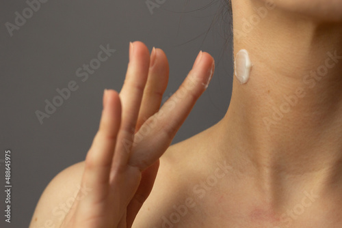 Obraz na płótnie Closeup of a young woman applying prescription retinoid to her neck. w salonie