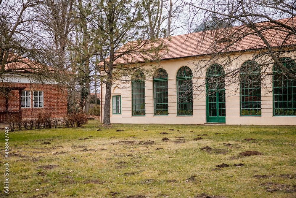 Veltrusy, Central Bohemia, Czech Republic, 5 January 2022: Rococo castle with park and garden, Romantic baroque chateau in sunny day, Classic style castle greenhouse with large wooden green windows