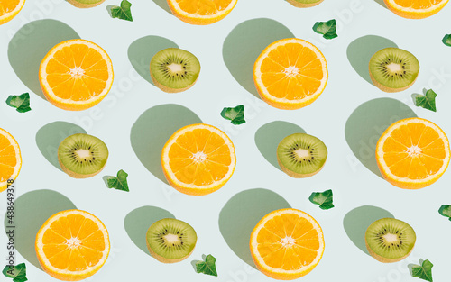 Pattern with oranges, kiwis and leaves on a pastel blue background. Top view of tropical fruits, banner background. Flat lay citrus fruit and kiwi.