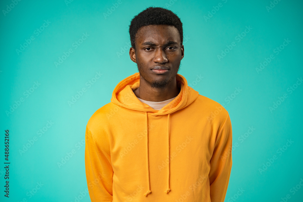 Fototapeta premium Portrait of young handsome afro-american guy sadly looking at camera in studio