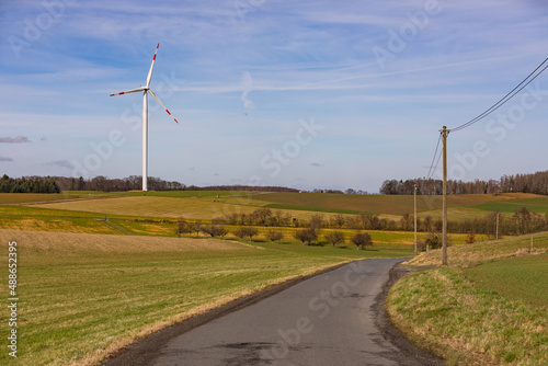 Ein Windrad und eine Stromleitung auf dem Land sichern den grünen Strom entlang einer Landstraße