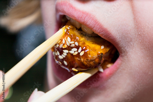 Girl eating sushi, close-up, mouth and sushi close-up. © mihail39