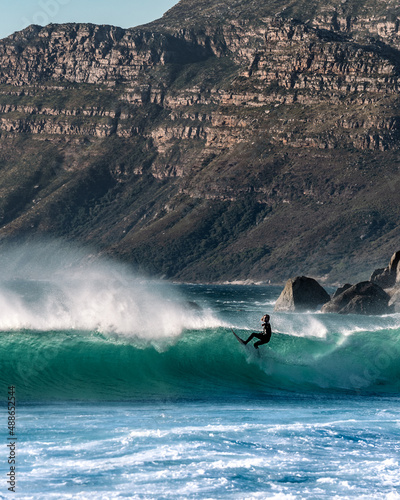 Surfer on blue ocean wave at sunset. Male surfer on blue wave in sunny day. Professional surfer in Cape Town, South Africa. Man surfing , isolated. Water sports. 