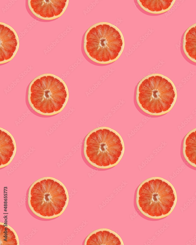 Trendy pattern made with grapefruit slice on pink background. Minimal fruit concept. Trendy pattern made with grapefruit slice on pink background. Minimal fruit concept.