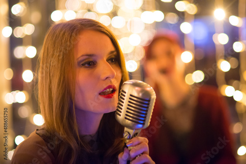 Woman singer singing in her band on the concert stage.