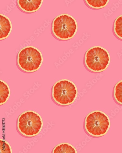 Trendy pattern made with grapefruit slice on pink background. Minimal fruit concept.