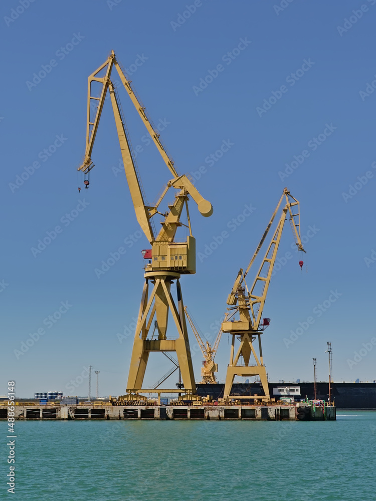 Yellow industrial cranes on a blue sky in the seaport of Cadiz, Andalusia, Spain 