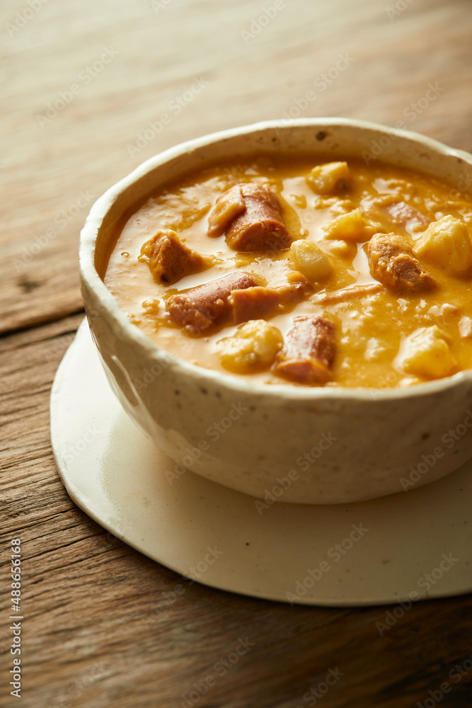 Mote pata is a traditional ecuadorian soup made from mote, pork, sausage and sambo seeds. It’s served on a white plate with a rustic, wooden and homey background. Mote pata is a traditional ecuadorian soup made from mote, pork, sausage and sambo seeds. It’s served on a white plate with a rustic, wooden and homey background.