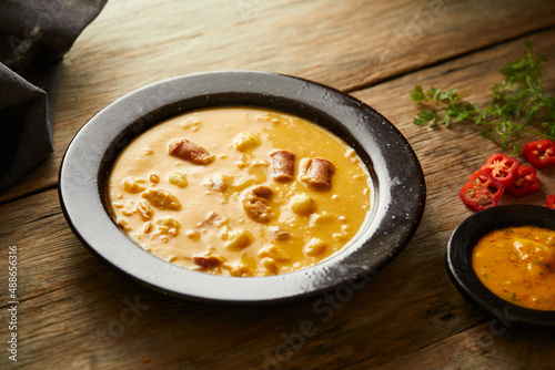 Mote pata is a traditional ecuadorian soup made from mote, pork, sausage and sambo seeds. It’s served on a white plate with a rustic, wooden and homey background. 