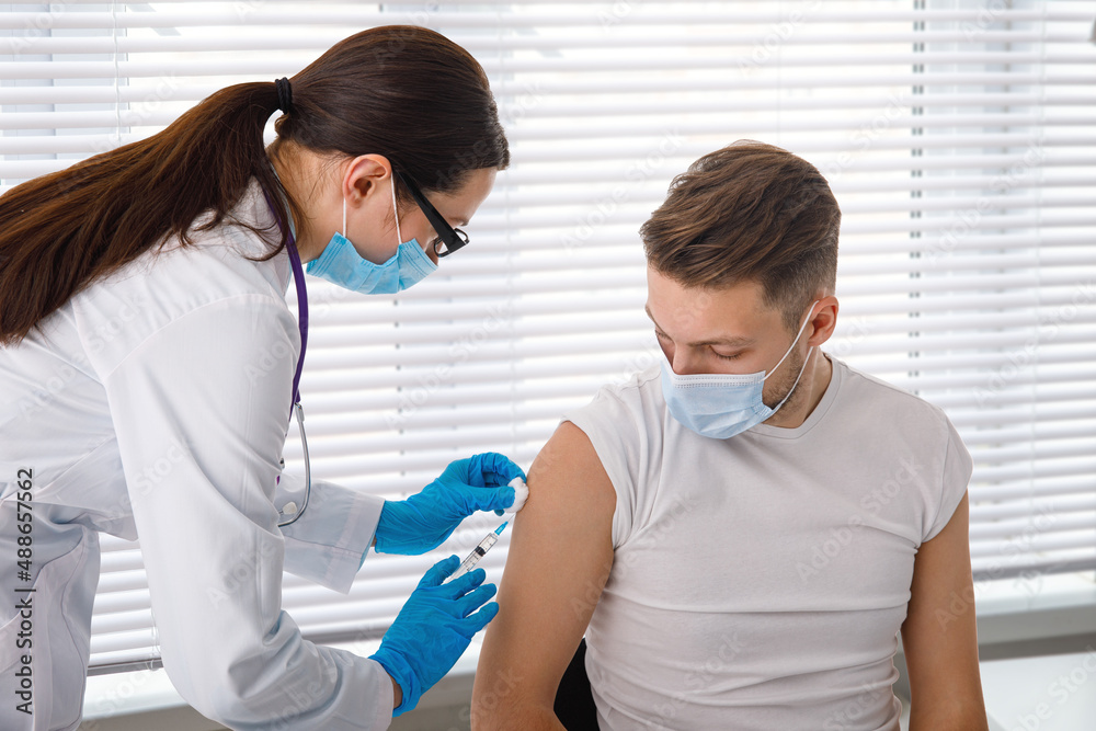 Obraz premium The doctor holds a syringe before giving an injection to a patient in a medical mask. Covid-19 or coronavirus vaccine. Vaccination of the population concept.