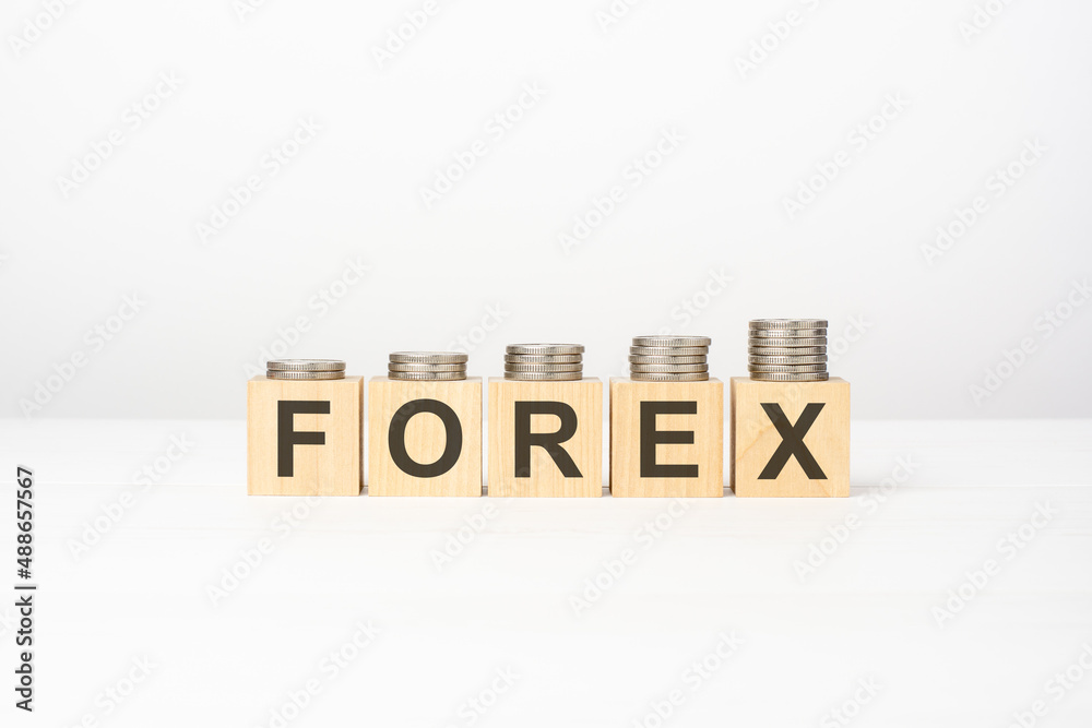 forex text written on wooden block with stacked coins on white background forex text written on wooden block with stacked coins on white background