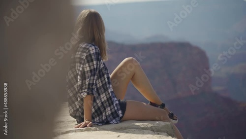 A young woman looking to Horseshoe Bend and Colorado river from the edge of 1000ft canyon in Glen Canyon National Recreation Area, Arizona, USA