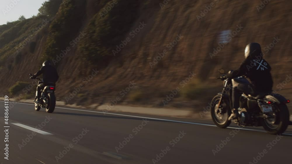 Motorcyclists riding beautiful bikes along a coastal highway. Back view of the bikers driving within cinematic mountainous landscape in California. High quality 4k footage Motorcyclists riding beautiful bikes along a coastal highway. Back view of the bikers driving within cinematic mountainous landscape in California. High quality 4k footage