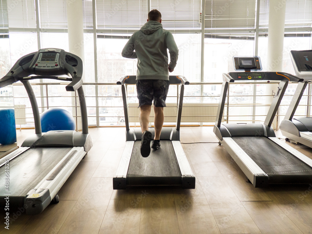 Fototapeta premium guy jogging on a treadmill in the gym. Fitness, workout and healthy lifestyle
