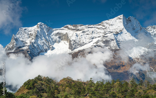 View to snow walls of Himalaya peaks above green forest
