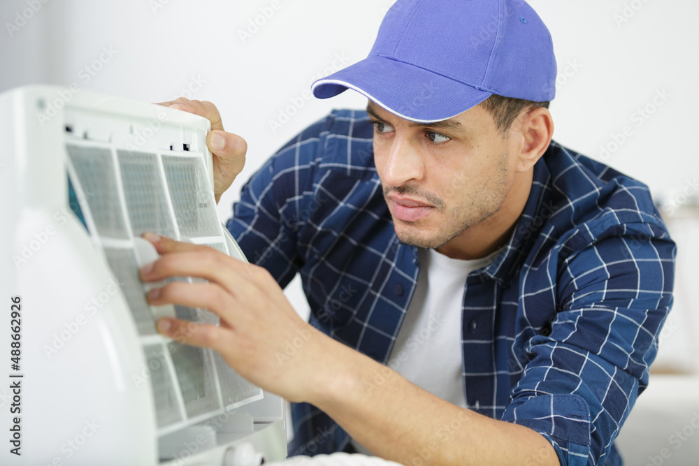 a professional electrician man is fixing the heavy air conditioner