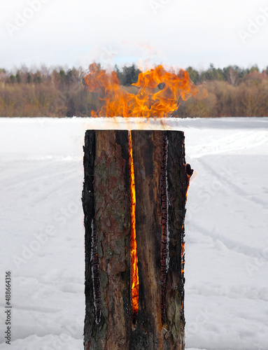 the fire from the Swedish torch or Canadian candle on the background of snow and forest photo