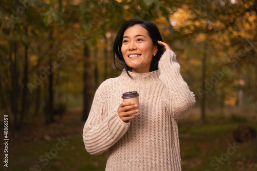 Enthusiastic millennial girl  with dark hair satisfied and optimistic smiling in a park on a autumn day.