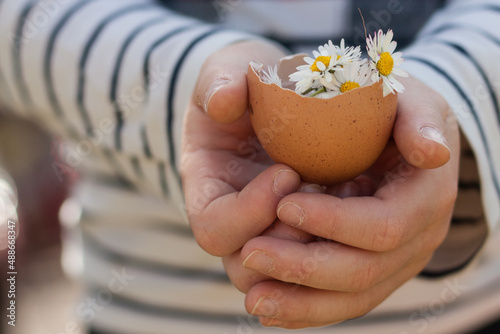 Mano sujetando huevo con flores