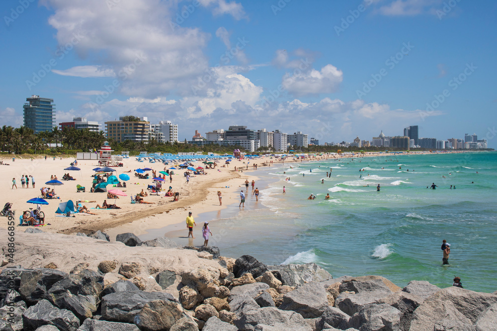 People sunbathing on a South Miami beach on a summer day under blue skies