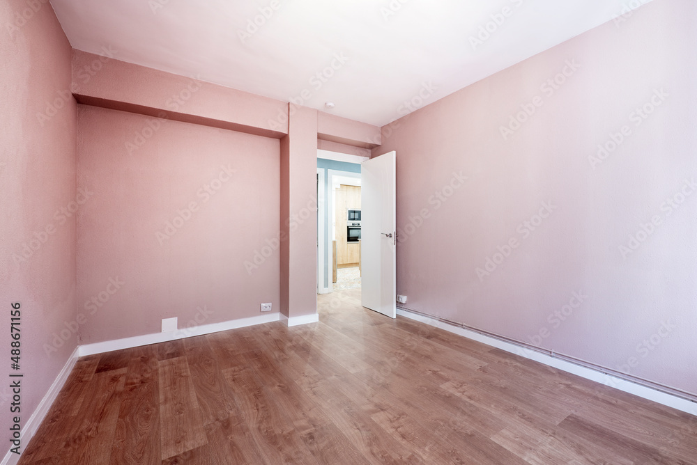 Empty room painted with pastel pink paint, wooden floor, white wood carpentry and white wooden door Empty room painted with pastel pink paint, wooden floor, white wood carpentry and white wooden door